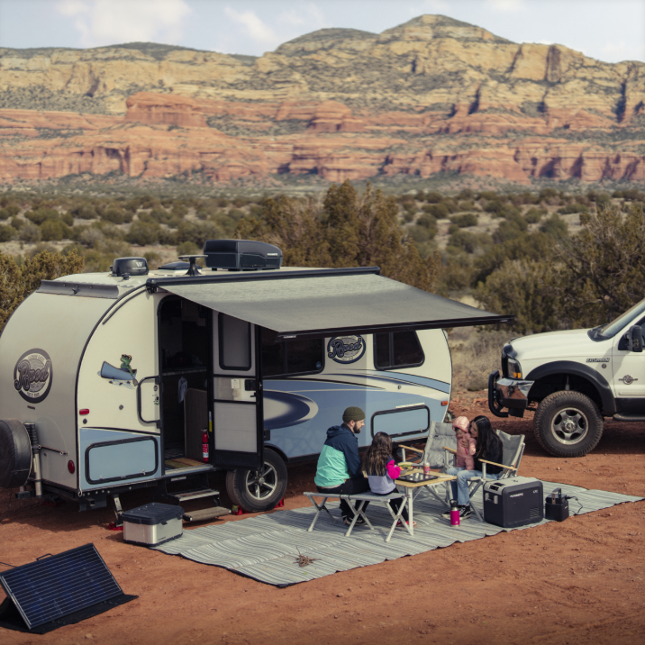 Dometic Air Conditioning Unit in colour black installed on top of towable camper trailer in desert camping scene with family eating