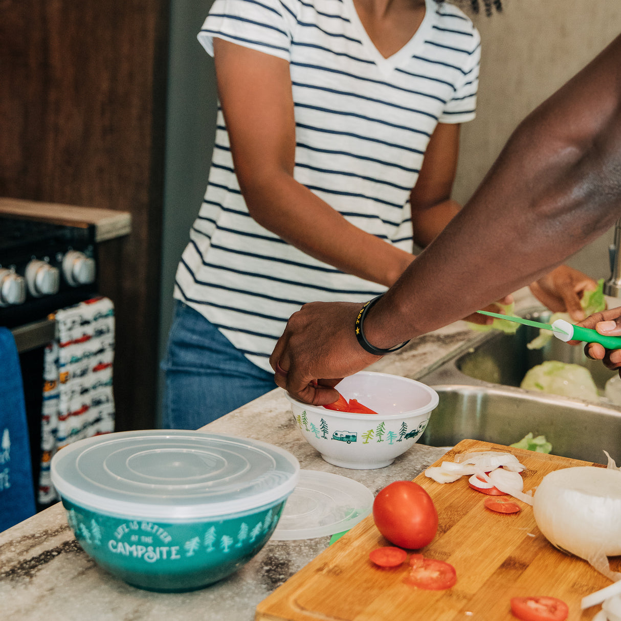 Couple preparing food inside an RV with a cutting board bowls and vegetables