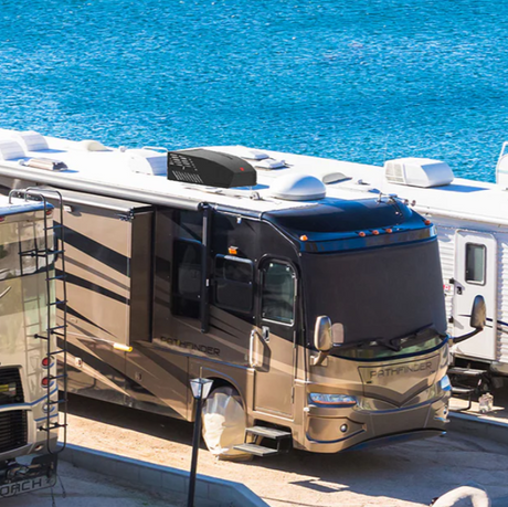 RV A/C units installed on motorhomes in front of ocean water on a sunny day